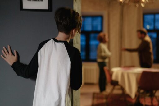 A child peers into the next room where their parents are arguing