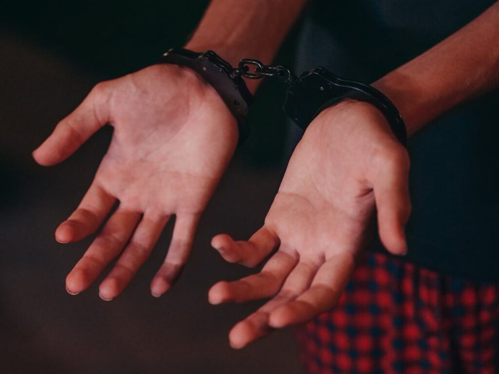 A pair of pleading hands bound by handcuffs